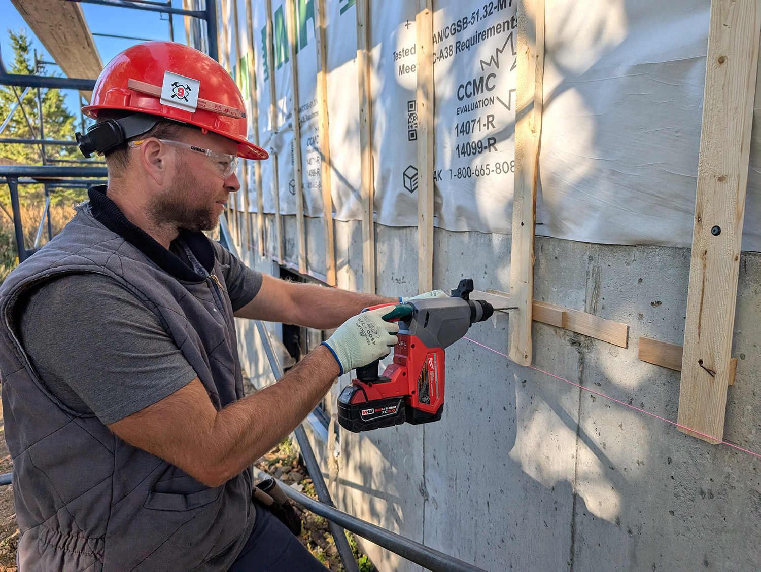 Un jeune homme utilise une perceuse pour solidifier une structure sur une maison
